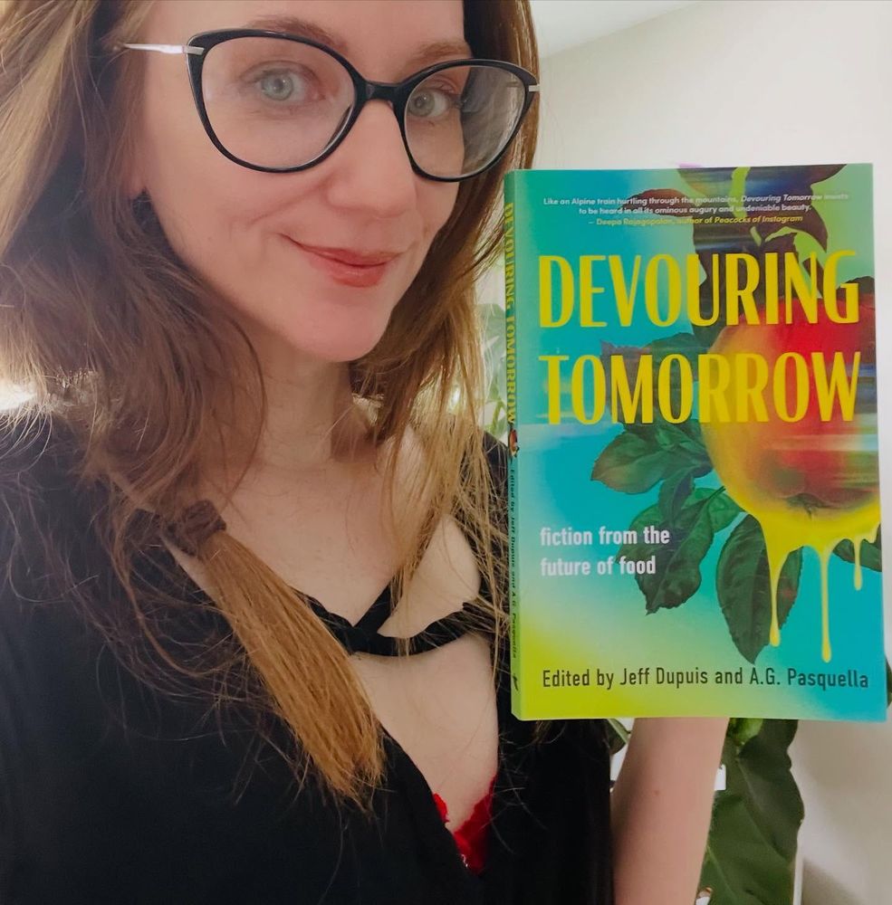 Sarah Marie smiles as she holds up a copy of DEVOURING TOMORROW