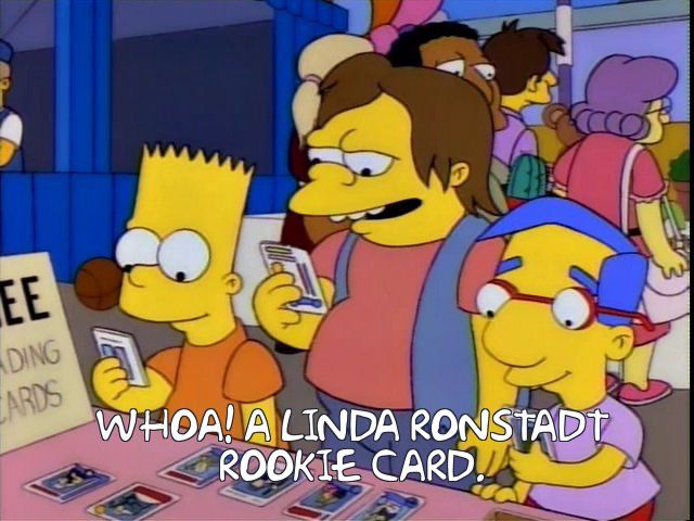 Bart, Milhouse and Nelson are looking at trading cards. Altered caption: “Whoa! A Linda Ronstadt rookie card.”