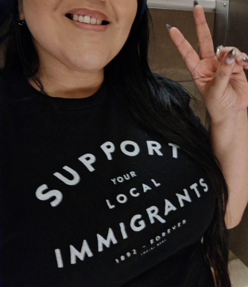Black tshirt with white lettering on it: Support your local immigrants 