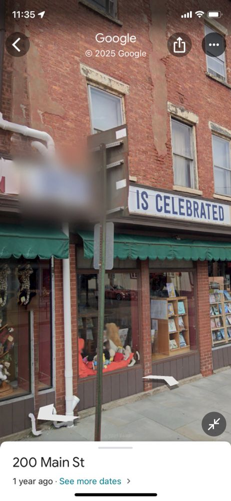 A screenshot of google maps. A sign over a bookstore reads “[redacted] is celebrated”.