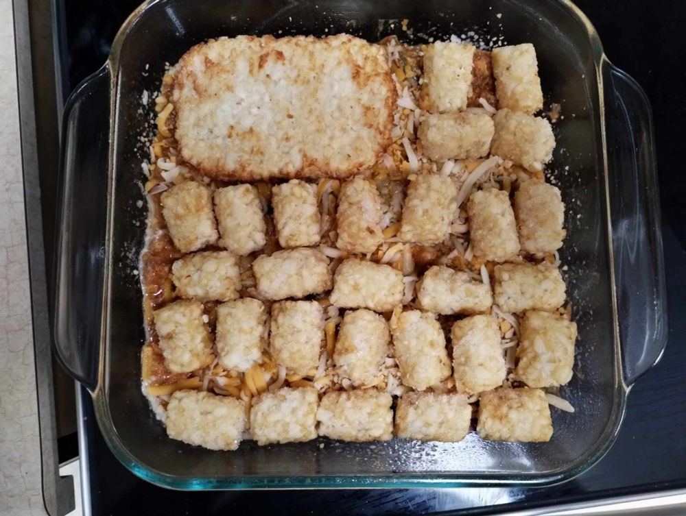 Tater tot casserole with three rows of vertical tater tots, three rows of horizontal tater tots, and a hash brown patty in the upper left where I did not have the remaining tots to cover the casserole.