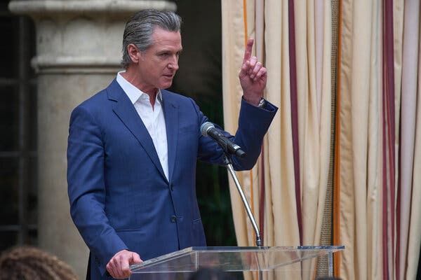Gavin Newsom at podium, no tie