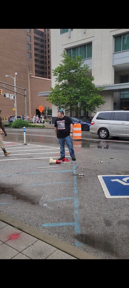 Crybaby maga.  On the ground are various D batteries, a MAGA hat, and two halves of a snapped flagpole.