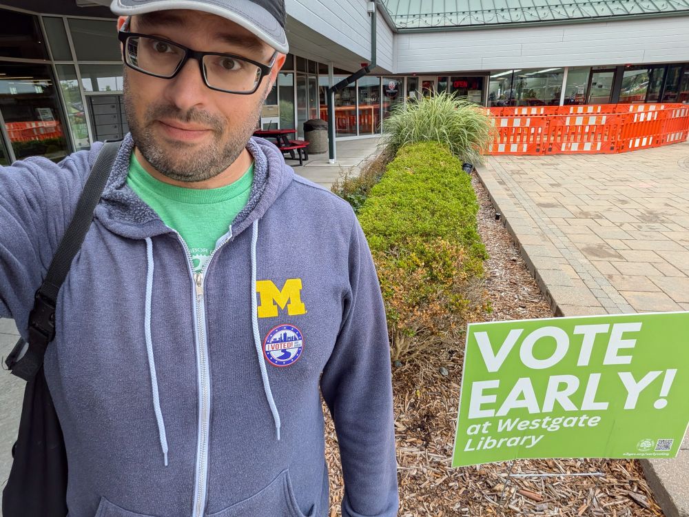 A selfie taken outside the Westgate branch, next to a sign that says "VOTE EARLY! at Westgate Library". I have an "I Voted" sticker on my hoodie.