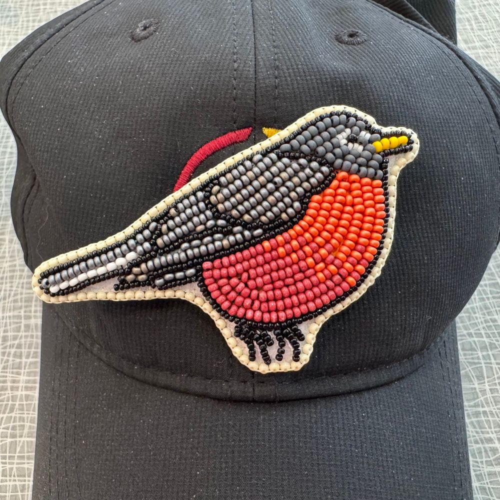 A beaded hat pin of a Robin in side profile, with lots of orange red beads making up the breast of this chubby robin, and grey and black beads for its back.