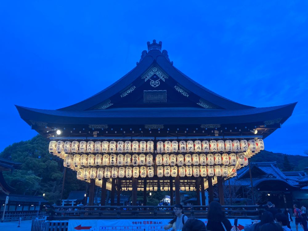 Temple in Japan, with three rows of lanterns hung under the roof, against a medium blue sky