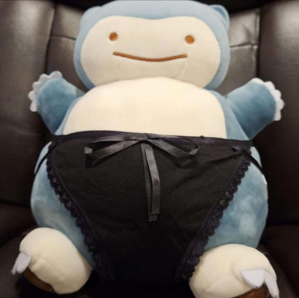 A snorlax plush in lacy black bikini style panties with a bow on the waistband