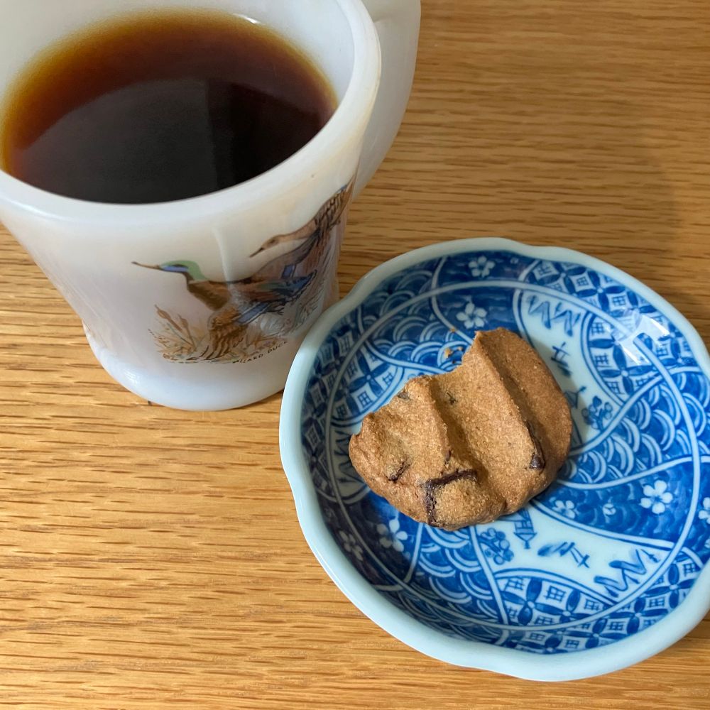マグに入ったコーヒーと、有田焼の小皿に乗ったチョコチップクッキー。半分齧られている。