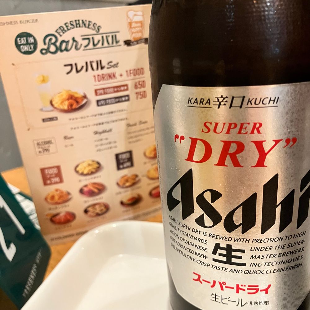フレッシュネスバーガーのフレバルのメニューとアサヒスーパードライの瓶の写真。