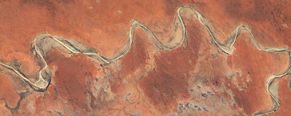 Satellite image of the Finke River in the Simpson Desert. The longitudinal dunes are deep orange-brown and the highly sinuous river is white sand.