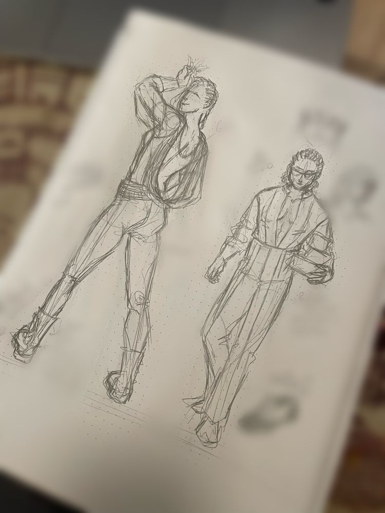 Foto de un cuaderno con la página desenfocada, salvo los dibujos de dos personajes vestidos de fiesta. A la izquierda, una muchacha muy alta, sujetando un muérdago por encima de su cabeza. Está dando la espalda y se ve el pedazo de escote de espalda que lleva en una preciosa blusa drapeada con transparencias, pantalón de cuero y botas heavys, el pelo está trenzado en el lado izquuerdo de la cabeza. A la derecha una mujer más bajita con pantalón de vestir con 4 pinzas, y una camisa abierta de cuello mao. El pelo está trenzado en el lado derecho de la cabeza, corto muy rizado. Lleva tres paquetes de regalos y parece que está caminando hacia el frente.