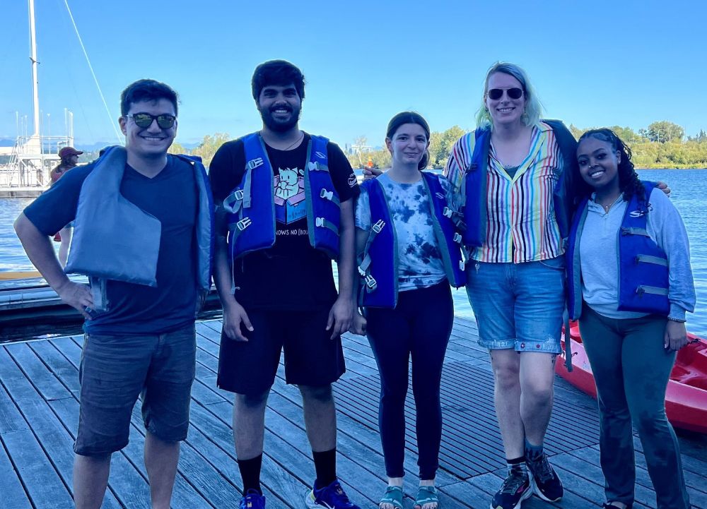 Members of the MatsuLab on a dock wearing life vests after kayaking.