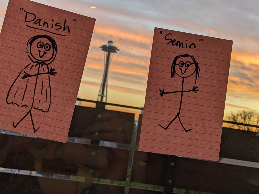 Post-its with stick figure drawings of the absent lab members, with the space needle in the background