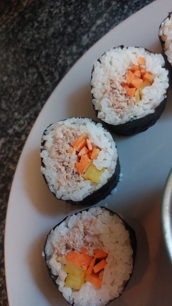 A close up of the three best pieces of kimbap. They contain carrot, yellow bell pepper, and tuna mayo