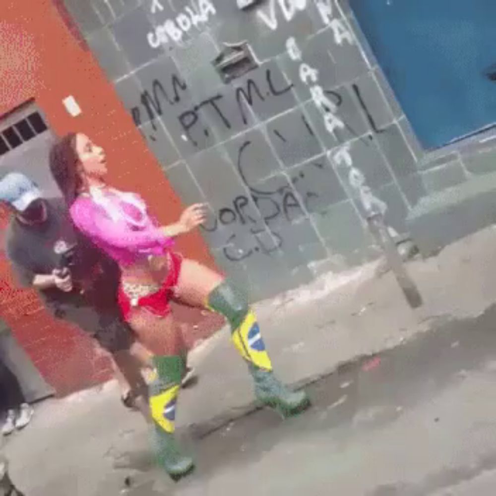 a woman is dancing in front of a wall with graffiti on it