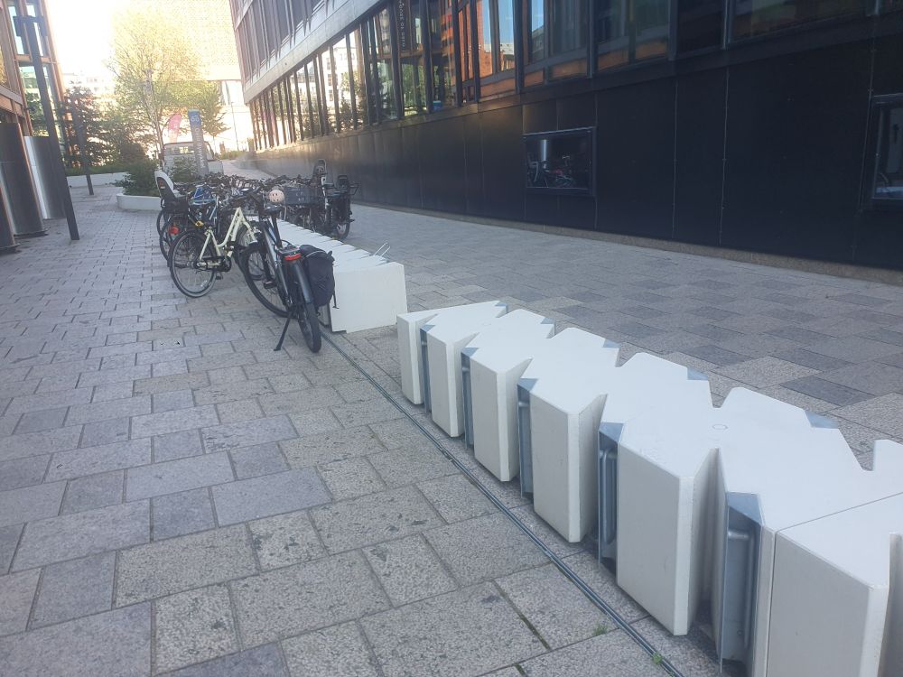 Sykkelstativ der man løfter ut en avlang metallstang fra en boksliknende sak for å låse sykkelen. 