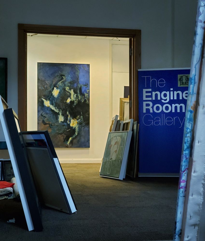 View through a doorway in a hallway, cluttered with unhung paintings, to a large blue abstract painting by Michael Doherty hanging on a wall beyond.