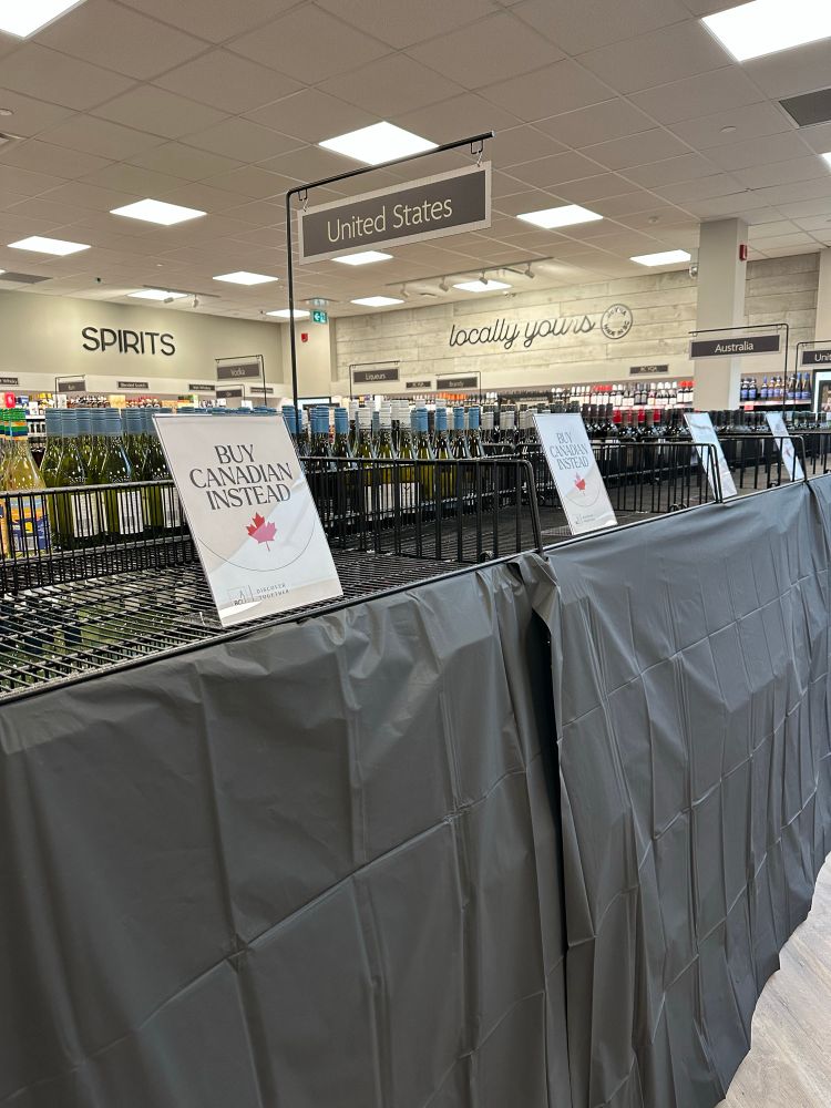 Empty wine shelves that used to hold American wine , now urging folks to buy Canadian instead 