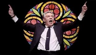  Peter Finch as Howard Beale in “Network” standing in front of a stained glass window