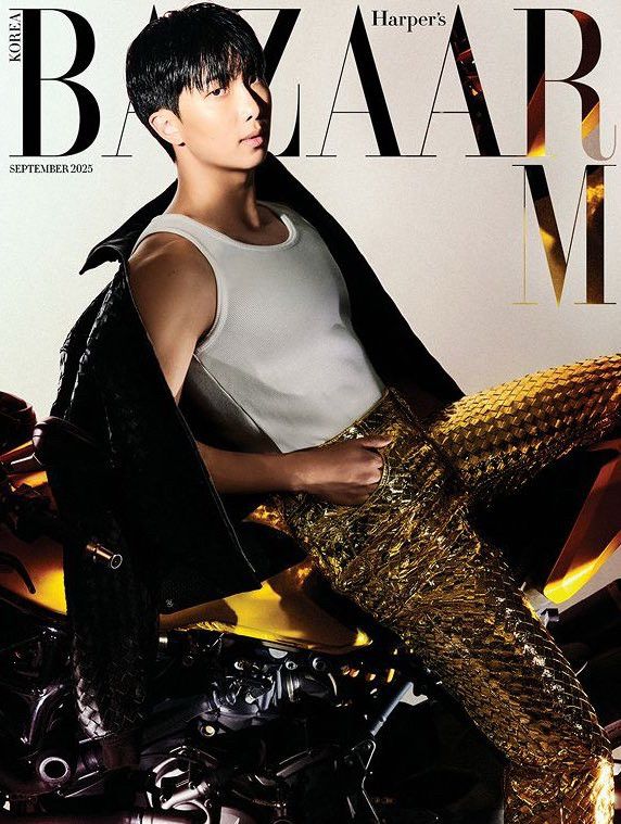 kim namjoon on the cover of harper’s bazaar september 2025 issue. he’s on a motorcycle leaning back and has his shoulder exposed under a bv leather jacket while wearing a white tank top. he has on sparkly golden woven like detailed pants. he looks delicious and i will eat him raw 