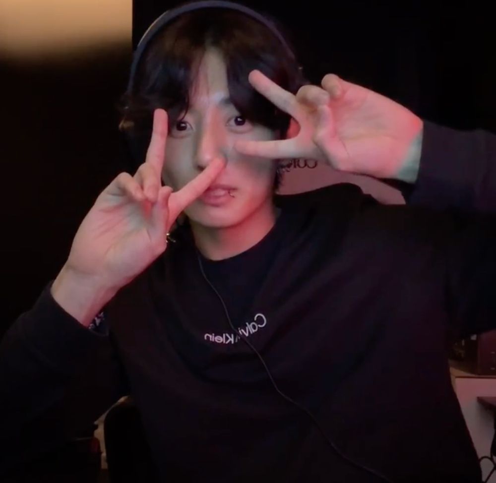 jungkookie during his live throwing two peace signs over his face