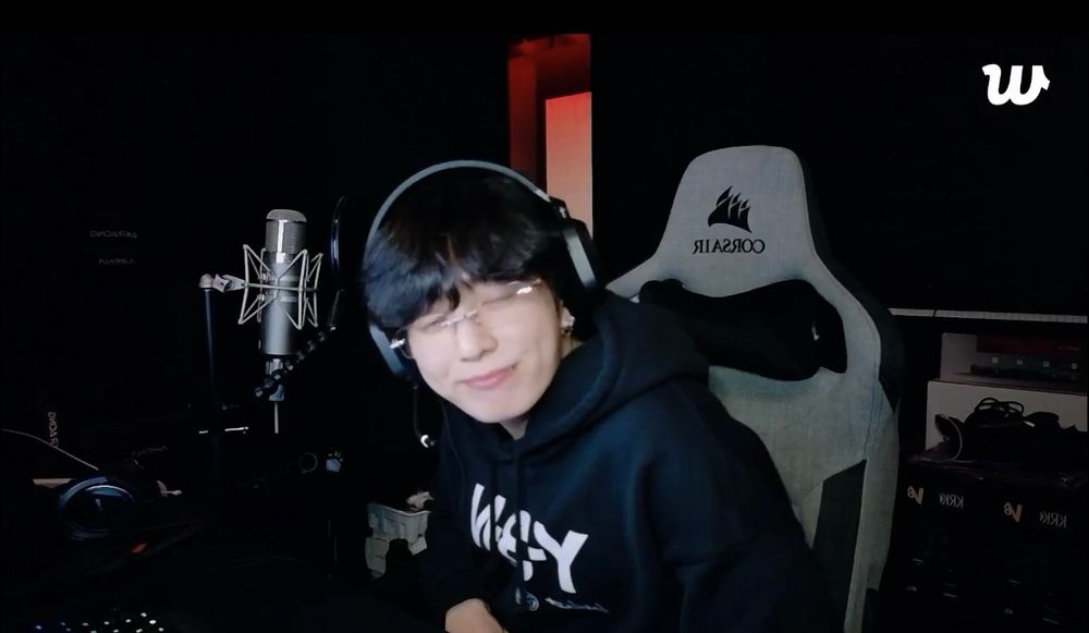 jeon jungkook in his gaming chair wearing all black and black headphones and glasses smiling cutely 