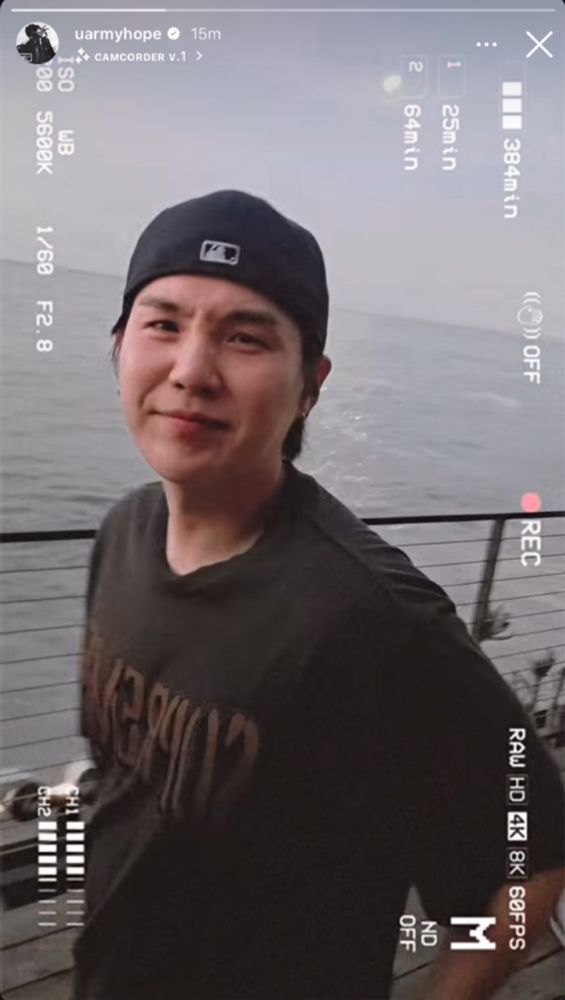 min yoongi in hobi's ig story making his cute scrunched up face to the camera. hes wearing a backwards cap on and a black shirt by the ocean. doesnt he know how precious he is? i think he does. he should know.