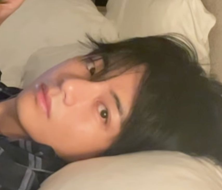 kim taehyung in bed glancing at the camera after taking a 4 hour nap