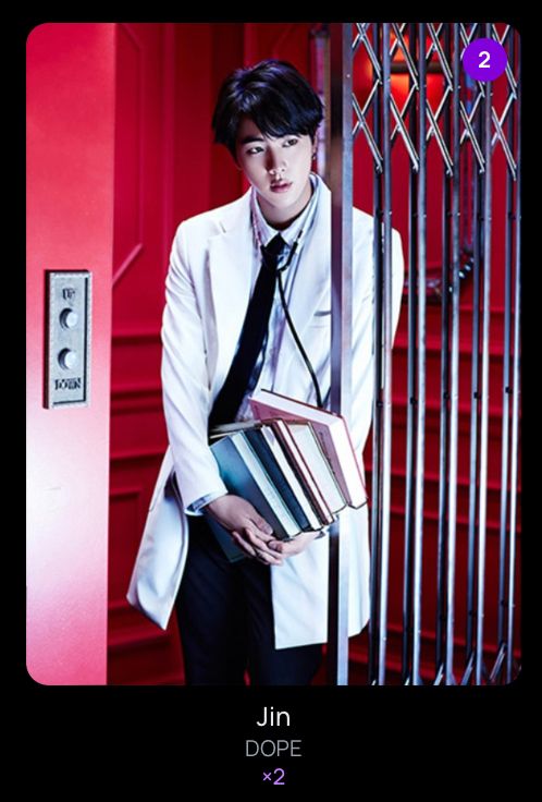 jin photocard from bcd website. it's the dope pc with him dressed as a doctor in a white coat holding text books leaning on a metal gated elevator
