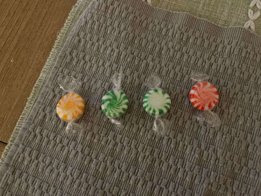 4 disc-shaped candies. Orange with swirls, green with swirls, green without swirls, red with swirls