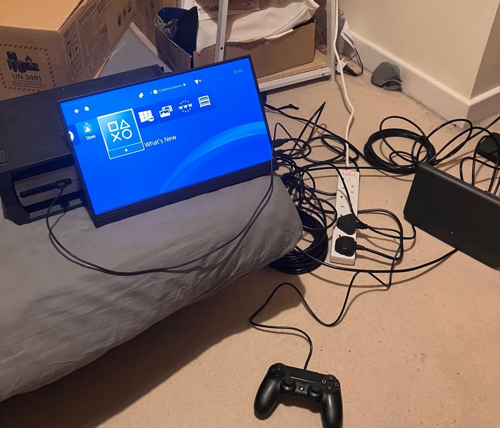 a photo of the mess that is my life whenever i have to do console updates because i don't have the space to have all of the bullshit out all the time so whenever i need to work on a console i have to set it all up on the sofabed with cables all over the place which i don't imagine is a safety hazard at all - ANYWAY the photo shows a ps4 devkit on a sofabed with a shitty usb monitor plugged in and then a bunch of cables everywhere 
