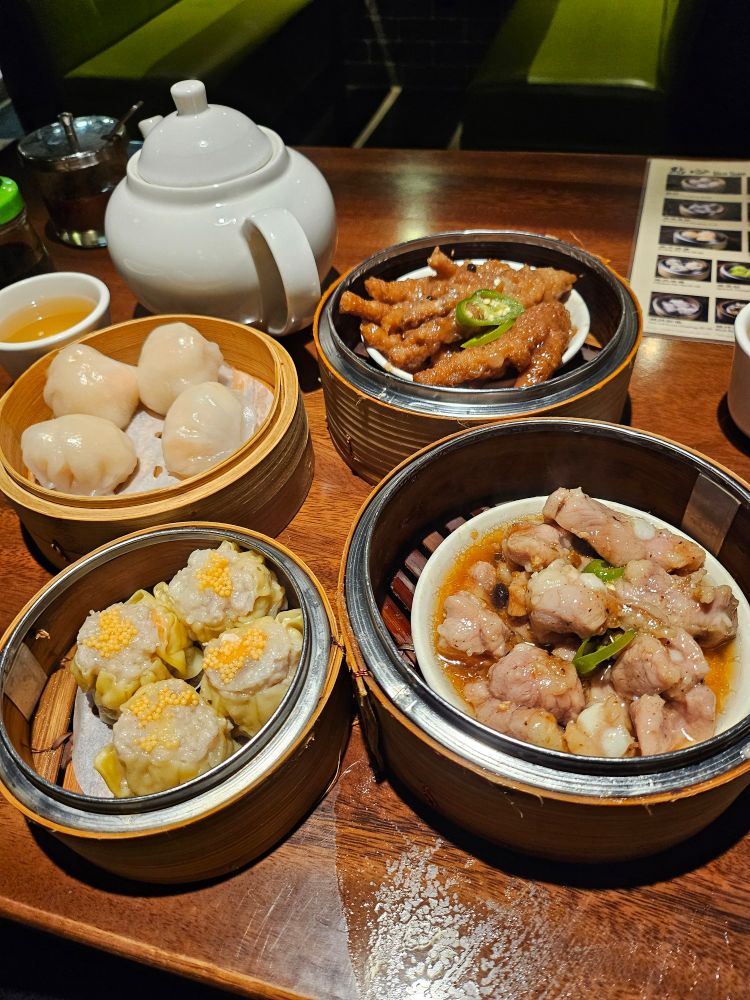 Four dim sum dishes served in their steamer containers.