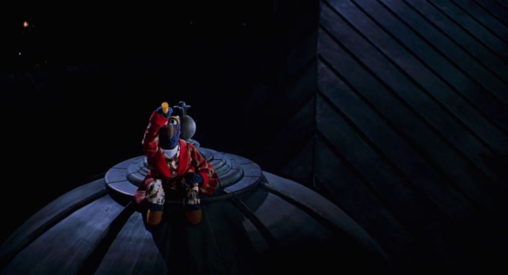 gonzo sits on a dome roof and peers into the night sky with a telescope