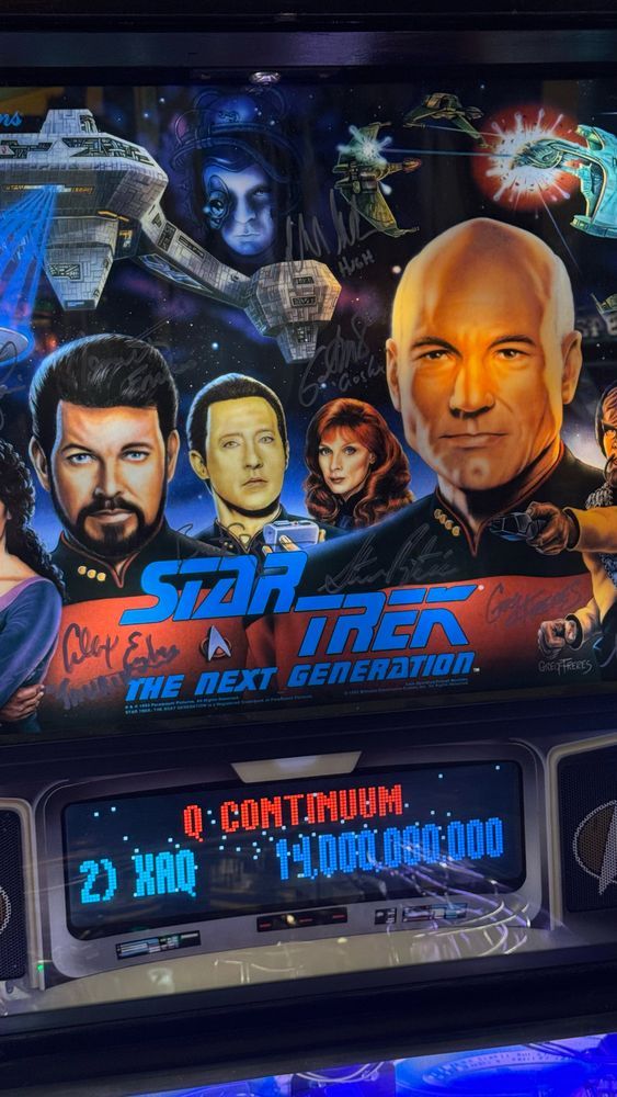 Closeup of the back of machine with cover art and signatures from actors like Hugh and Taurik