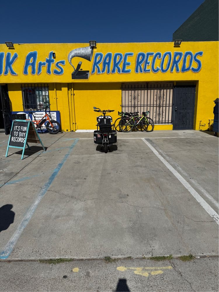 A cargo bike taking up 1/9 of the space of a parking spot meant for a car. The parking lot is in front of Folk Arts Rare Records