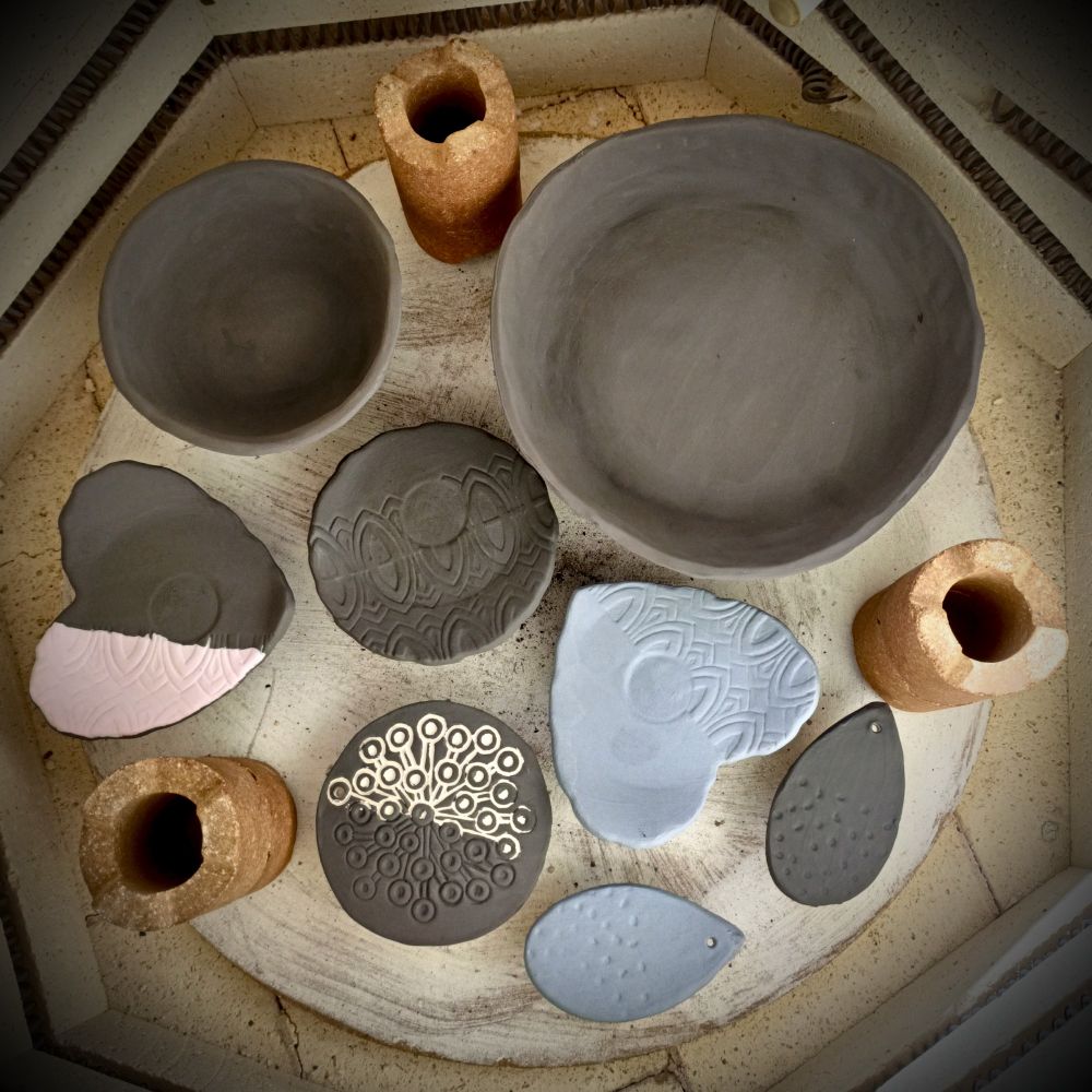 Kiln loaded with unfired glazed pottery, including 2 pinched bowls, 3 incense cone holders and 2 raindrop glaze tiles.