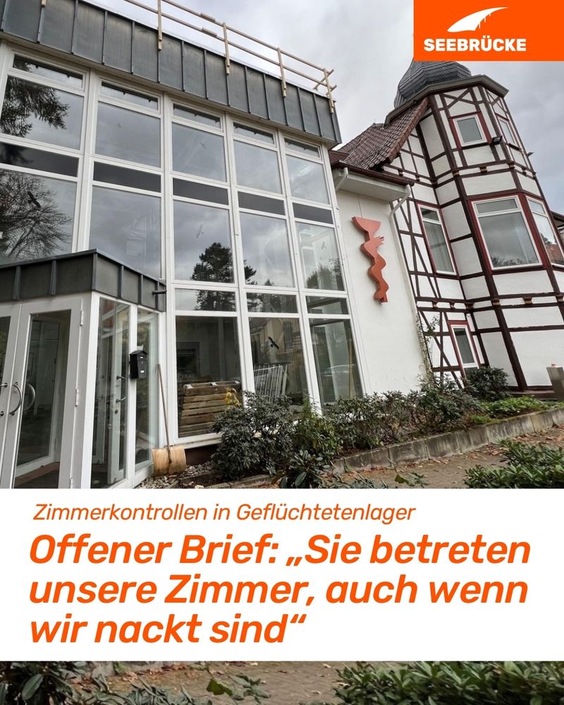 A building can be seen in the background.
At the bottom of the image is a white box. Inside it is written: "Room inspections in refugee camps. Open letter: You enter our rooms, even when we are naked."
At the top right is the Seebrücke logo.