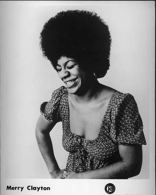 A photo from sometime in the 1970s of Merry Clayton. Its a more candid shot with her smiling wide, seemingly holding in some laughter. Shes in a square neck peasant blouse and has an afro. Its rad as hell.