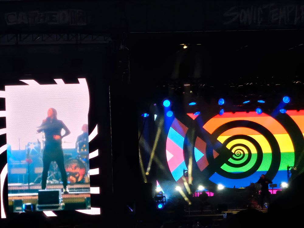 Motionless in white performing voices live and showing a large progress pride flag