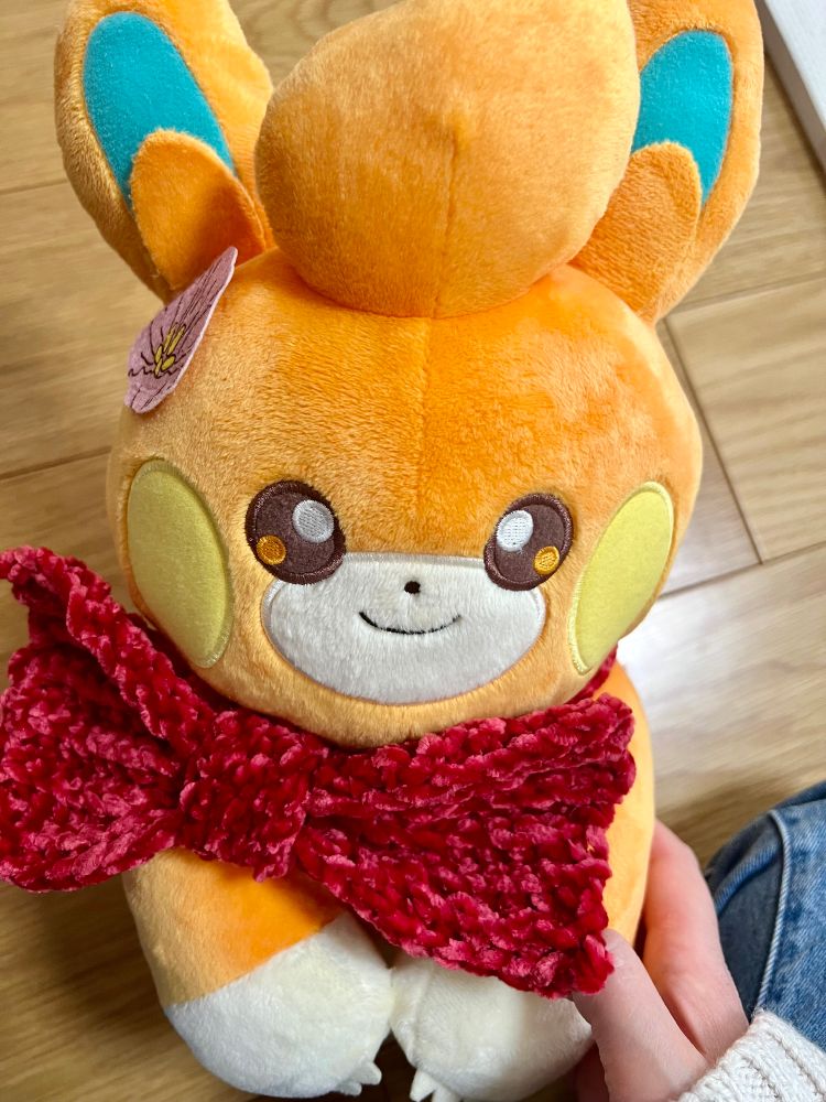 ポケモンのパモの首元にベルベット調の毛糸で編んだ、赤いリボンを巻いている画像