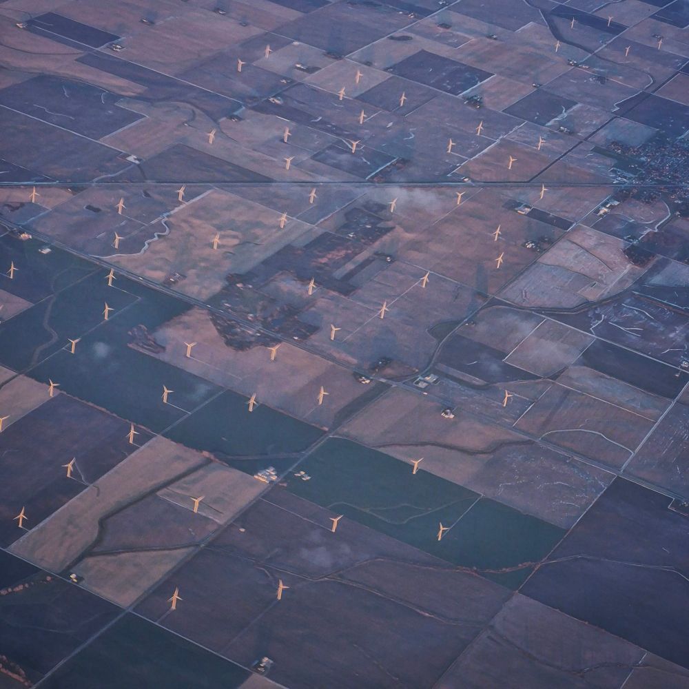 a blurry photo of wind turbines lit up by the setting sun