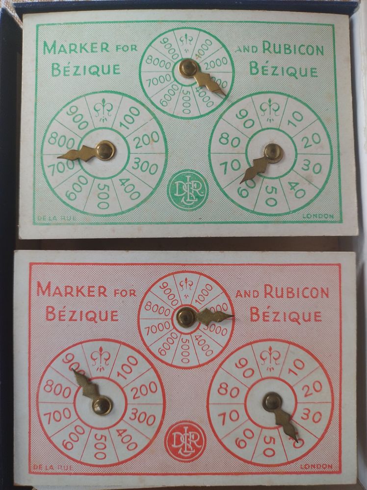 Two scoring cards for Bezique, green and pink, with a makers logo, saying "Marker for Bezique and Rubicon Bezique".