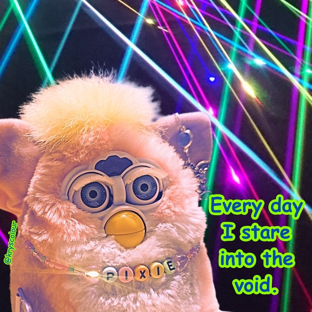 Furby baby with laser backdrop staring into the void and words saying thus.