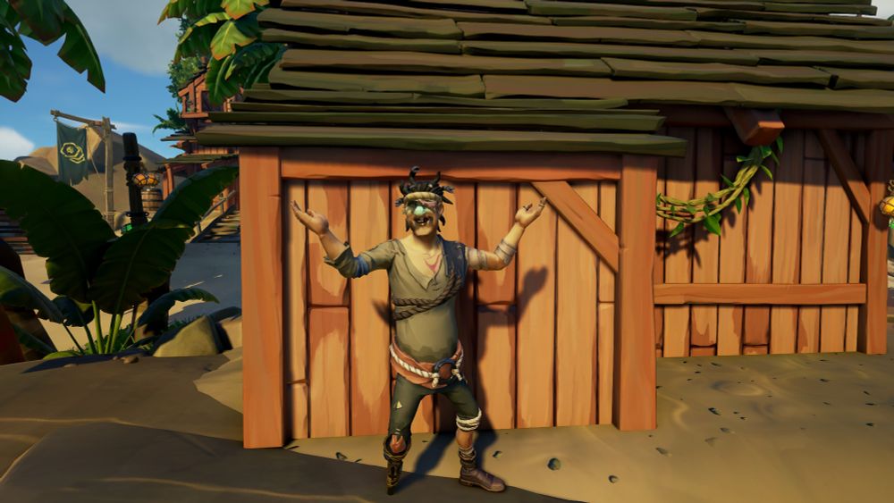 A ghoulish pirate stands presentably against the wooden wall of a shop in the game Sea of Thieves. He's wearing a worn down boot on one leg and a ramshackle pegleg on the other. His pants are little more than tatty rags and his belt is little more than rope attached to an iron ring over a salmon sash. He's wearing a tattered beige shirt with a dark brown leather pauldron. His face in covered in ghoulish makeup and a ratty head band sits on his head below a head of wild and frayed hair.