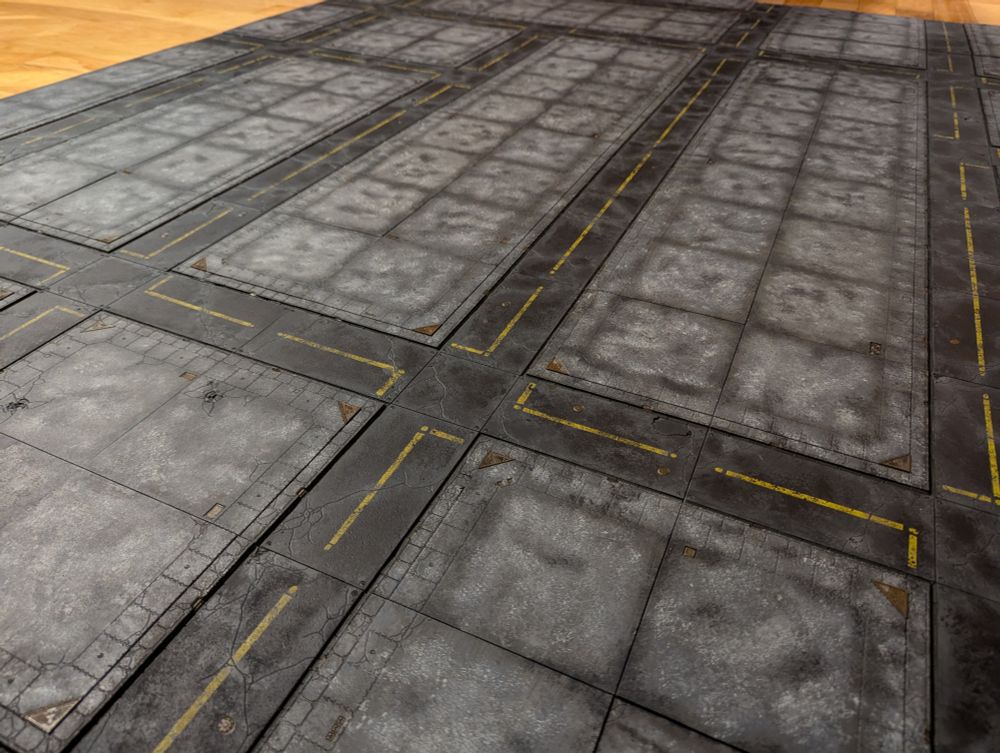 A close up of a  full 6'x4' set of Legions Imperialis scale road tiles fully painted in a grey and black scheme complete with road markings.