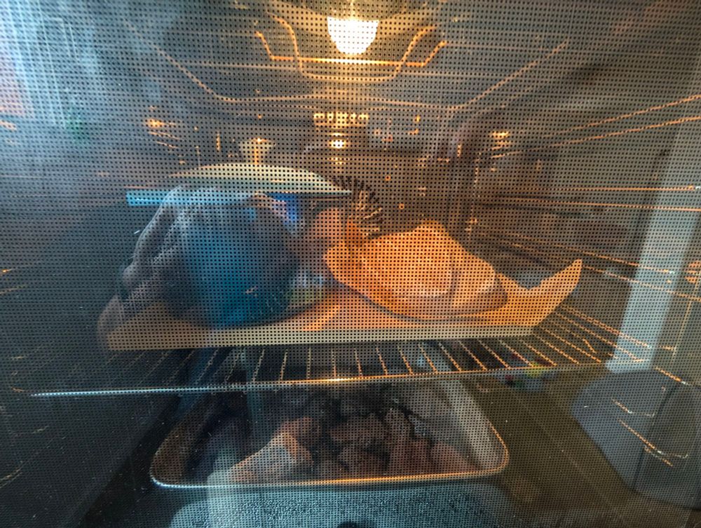 An oven with a pizza stone and on top of it we see a Dutch oven on the left side (with a bread inside) and on the right side there's another sourdough loaf.
On the bottom we can see some recipients with water and lava stone to generate steam