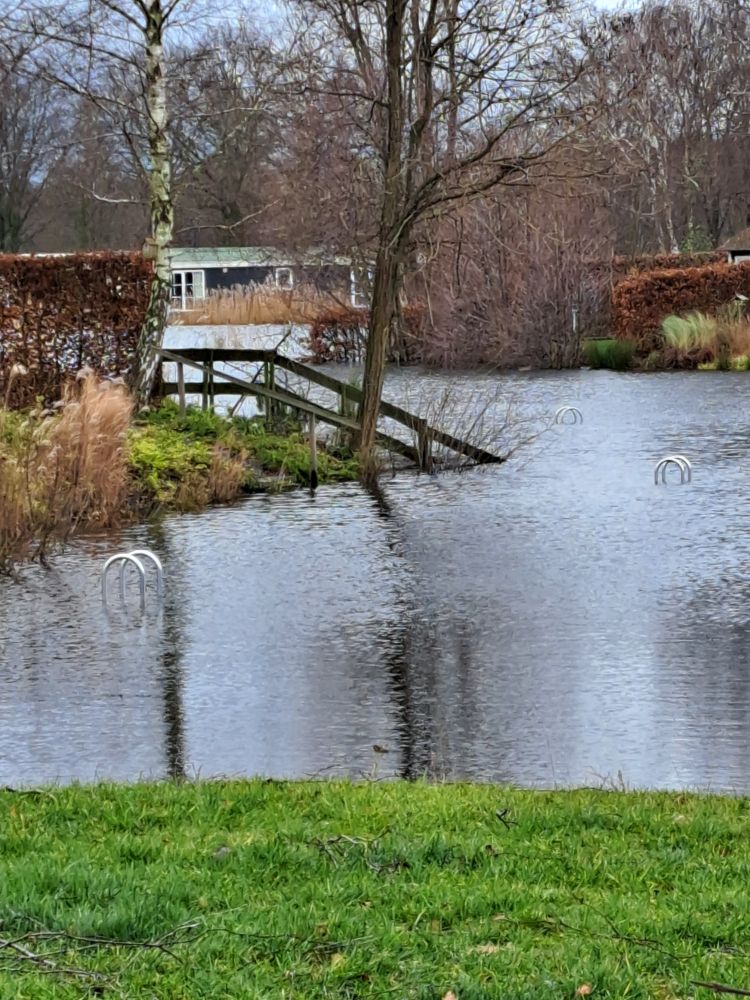 Ik stond langs een watertje waar bij diverse huisjes de steigers zo ver onder water staan dat alleen een stukje van de trapleuning te zien is.
