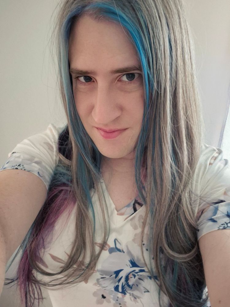 Me in a white top with blue flowers on it with my new hair that is blue and purple and grey.