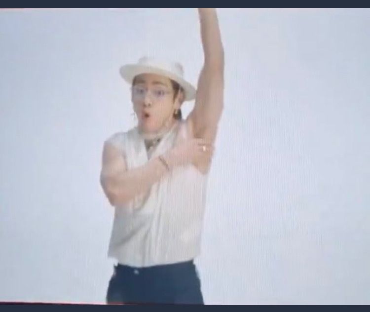 Screenshot of the now-deleted behind the scenes of Tae goofing around during Butter MV filming. He’s got one arm up and his other hand covering his armpit as if he was a 1940s pinup. But he is wearing Sofia from Golden Girls glasses on a chain and a straw boater hat. It’s a lot to take in 