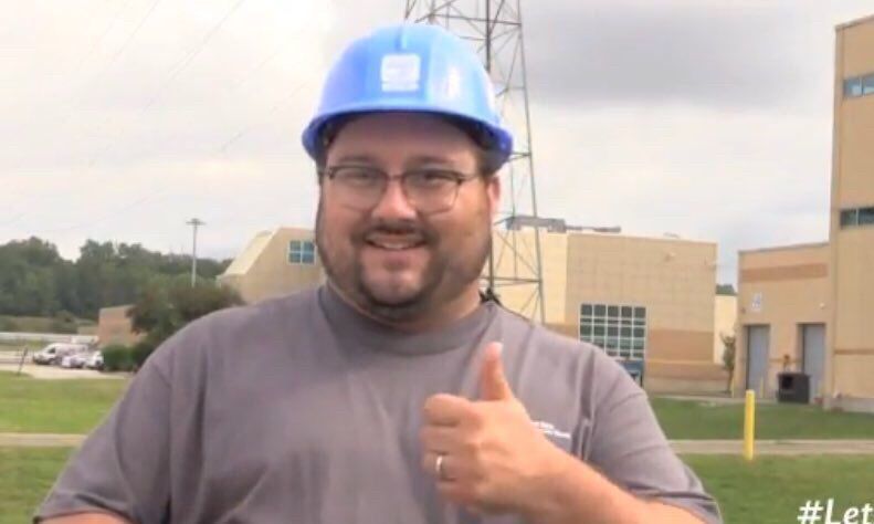 man in a blue hard hat gives a thumbs up